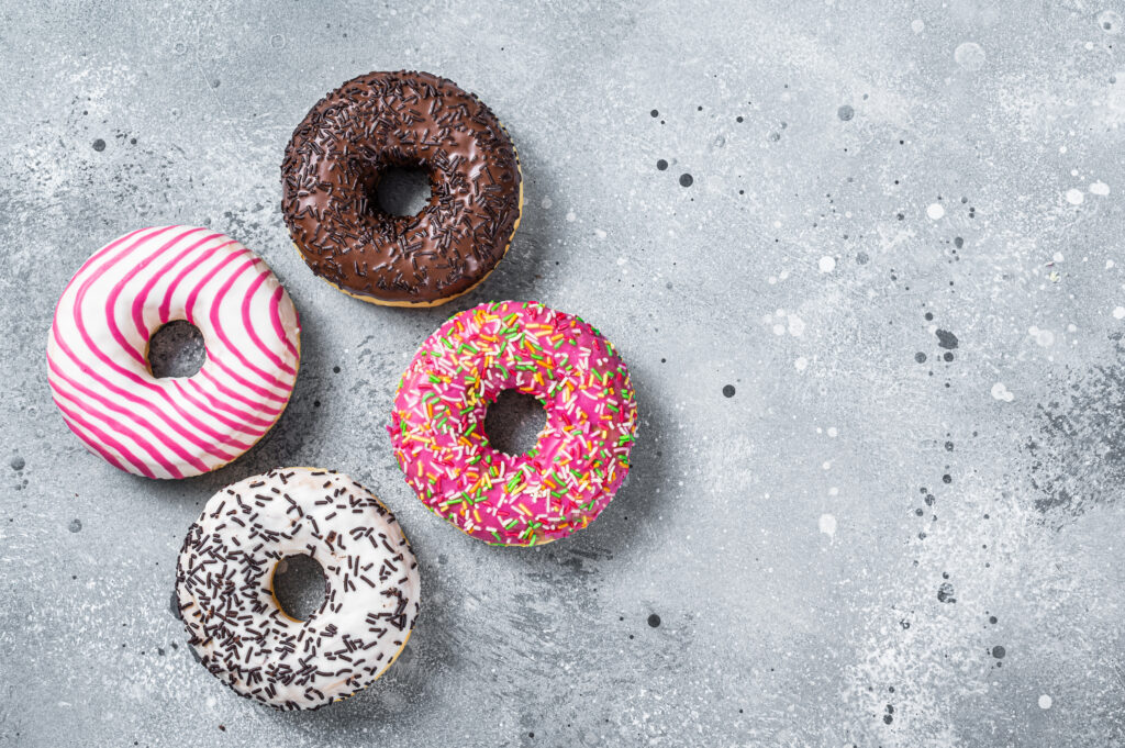 Assorted glazed donuts on a kitchen table. Gray background. Top view